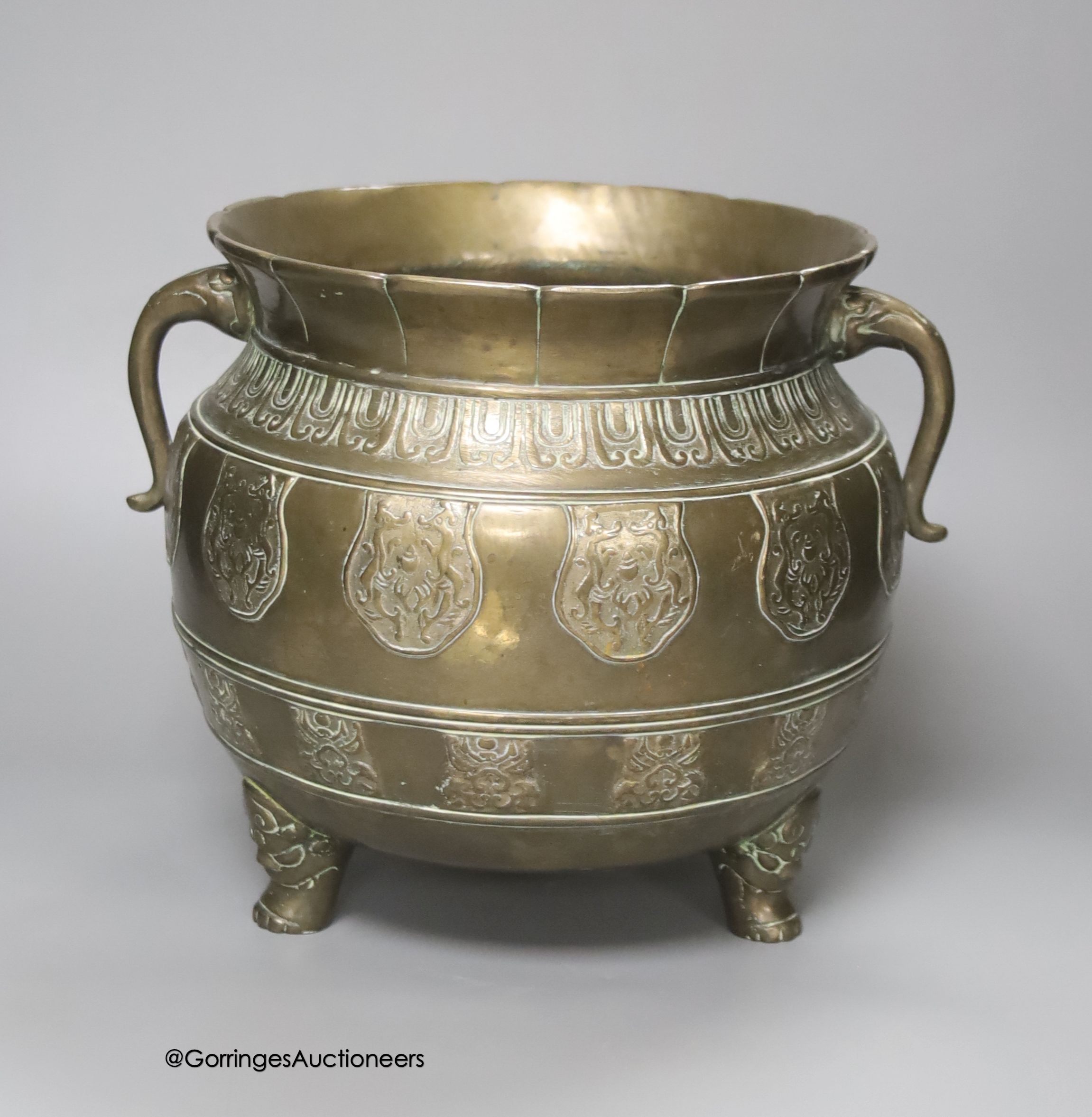 A Chinese or Japanese bronze two handled vessel, on cast feet, 22cm